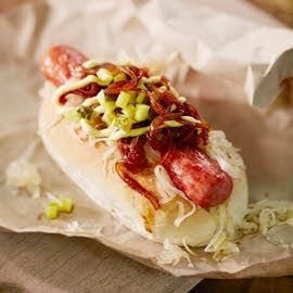 Hot-dog avec de la choucroute, des oignons caramélisés et du pickels